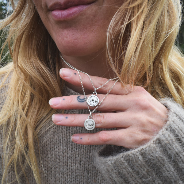 Close-up of a person wearing two silver necklaces with circular pendants.
