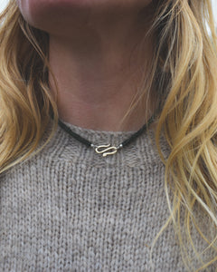 Person wearing a serpent necklace with a blurred background