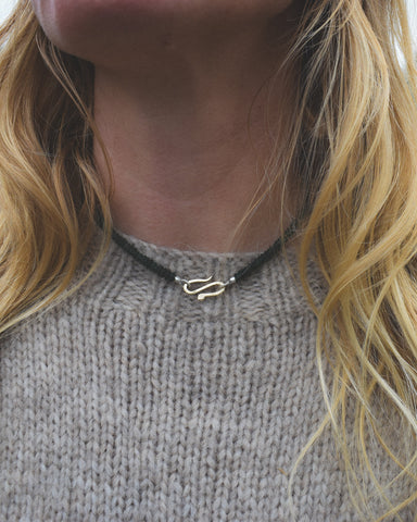 Person wearing a serpent necklace with a blurred background
